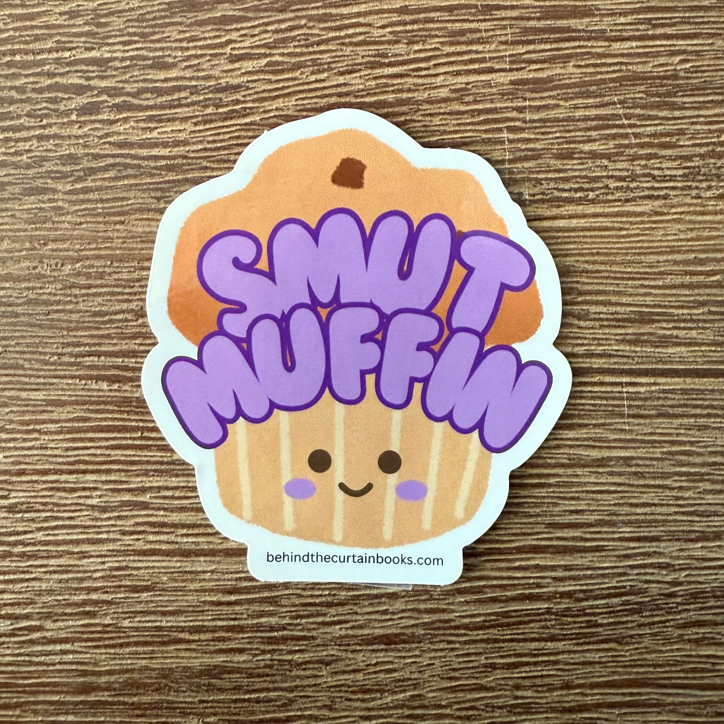 Sticker of a muffin with 'Smut Muffin' text on a wooden surface
