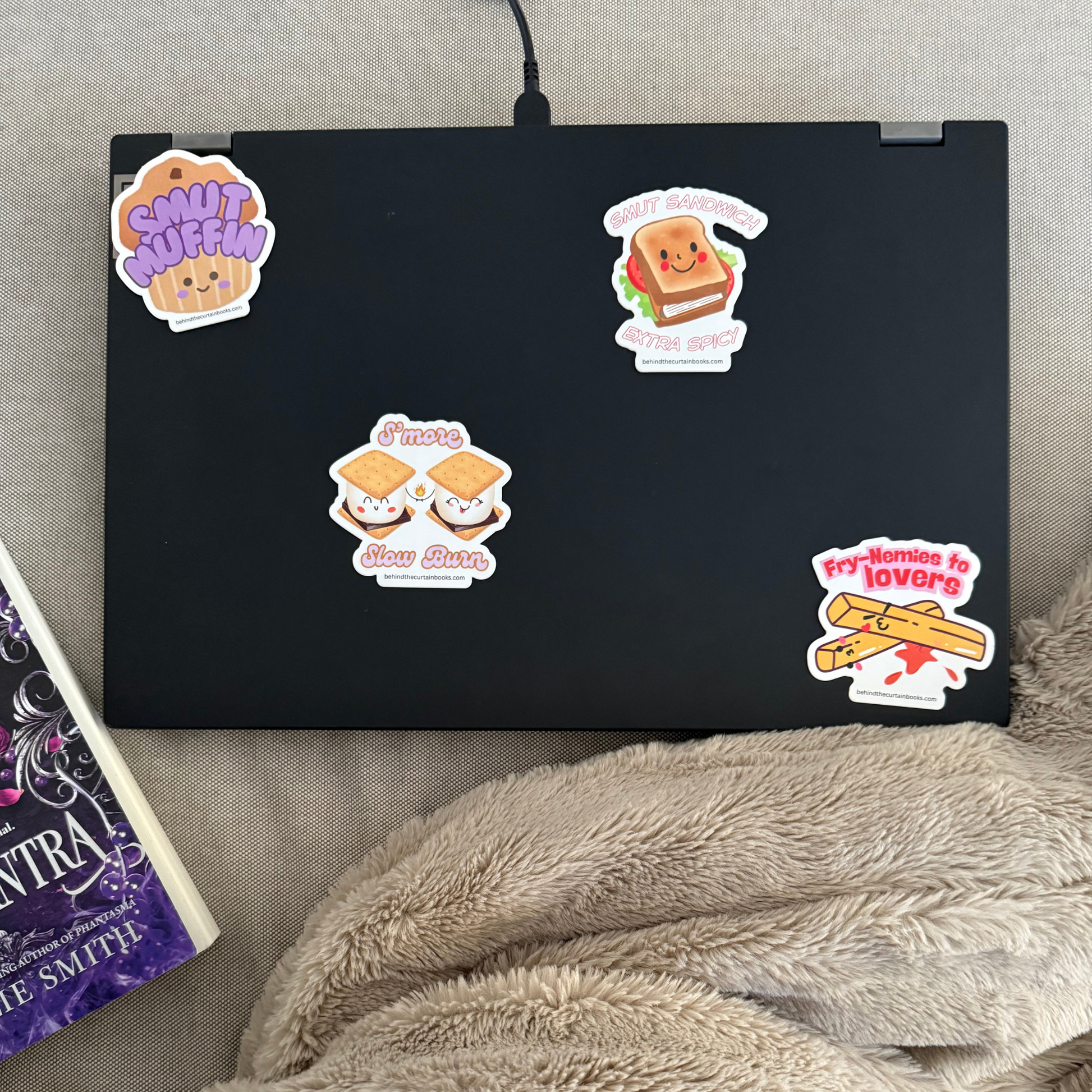 Black laptop with colorful stickers on a gray surface